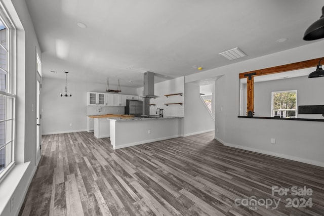 unfurnished living room featuring dark wood-type flooring, sink, and an inviting chandelier