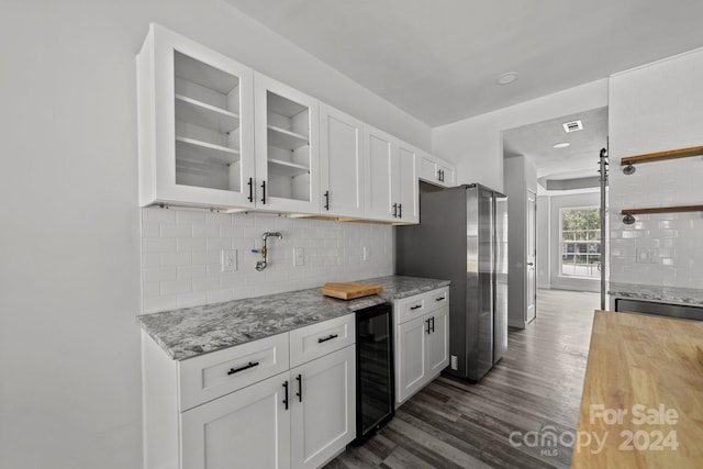 kitchen featuring stainless steel fridge, white cabinetry, dark hardwood / wood-style floors, light stone countertops, and beverage cooler