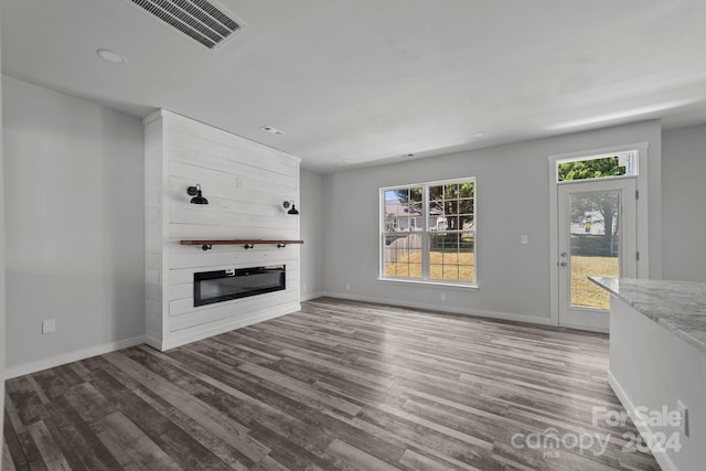 unfurnished living room with wood-type flooring and a large fireplace