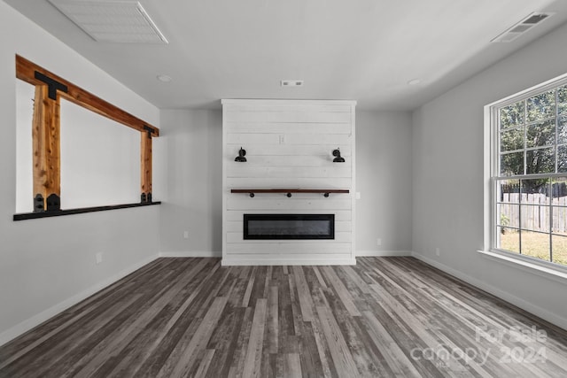 unfurnished living room with a large fireplace and dark hardwood / wood-style flooring