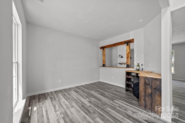 unfurnished living room featuring bar area and hardwood / wood-style flooring