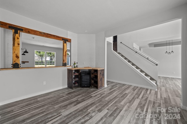 unfurnished living room featuring hardwood / wood-style flooring and indoor bar