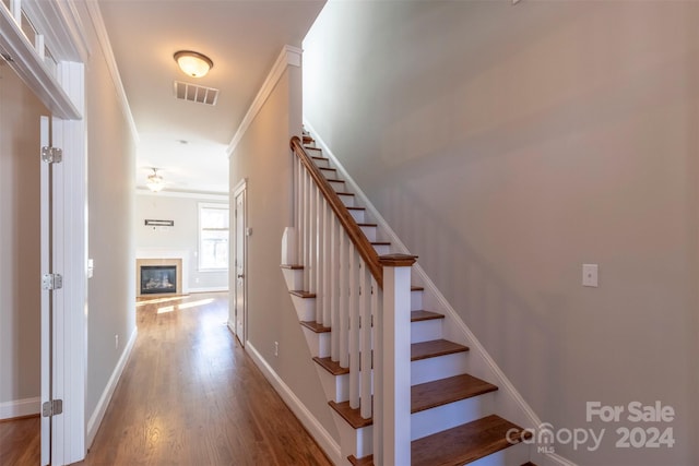 stairs with ceiling fan, hardwood / wood-style floors, and ornamental molding