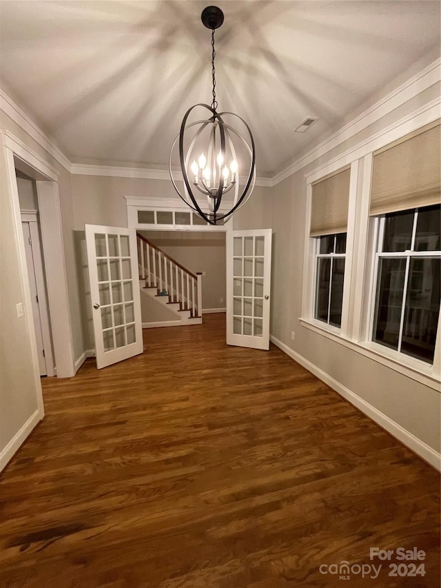 unfurnished dining area with ornamental molding, dark hardwood / wood-style flooring, and a notable chandelier