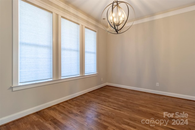 empty room featuring ornamental molding, hardwood / wood-style floors, and a chandelier