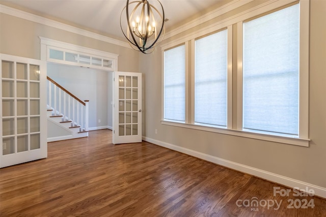 unfurnished dining area featuring a notable chandelier, french doors, hardwood / wood-style flooring, and crown molding