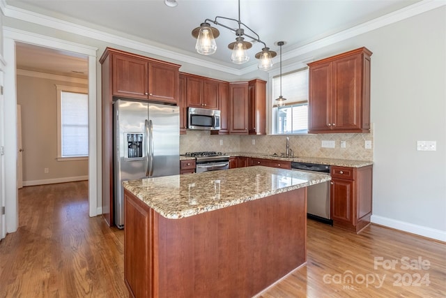 kitchen with stainless steel appliances, decorative light fixtures, a kitchen island, and hardwood / wood-style floors