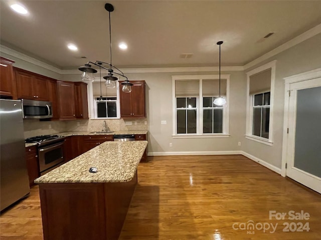 kitchen featuring stainless steel appliances, decorative light fixtures, a center island, and wood-type flooring