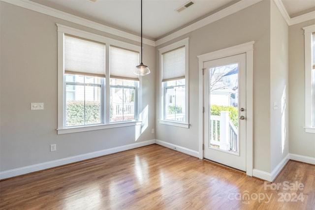 entryway featuring wood-type flooring, a healthy amount of sunlight, and crown molding