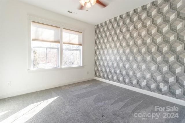 empty room featuring ceiling fan and carpet