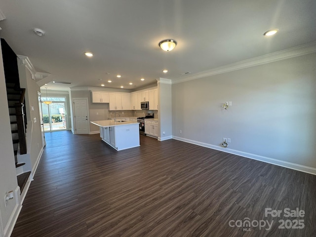 kitchen with a kitchen island, open floor plan, stainless steel appliances, light countertops, and white cabinetry