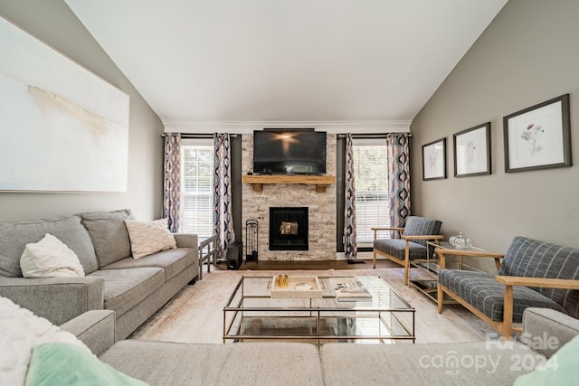 living room with light hardwood / wood-style flooring, a stone fireplace, lofted ceiling, and a wealth of natural light