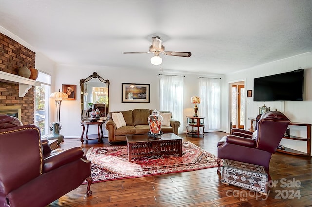 living room with a brick fireplace, ceiling fan, a textured ceiling, and dark hardwood / wood-style flooring