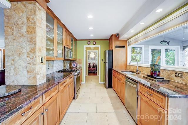 kitchen with dark stone countertops, backsplash, sink, and stainless steel appliances