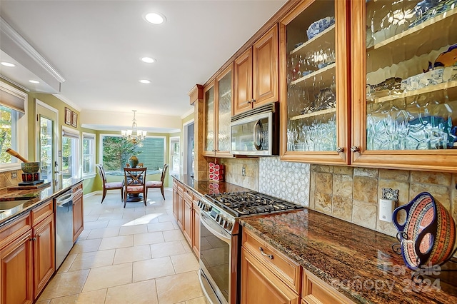 kitchen featuring stainless steel appliances, decorative backsplash, a chandelier, decorative light fixtures, and dark stone countertops