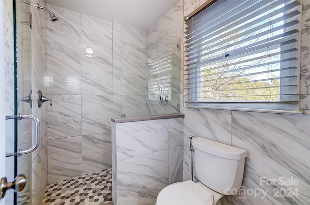 bathroom with toilet, tile walls, and a shower with door