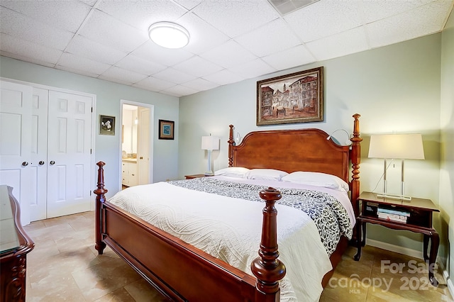 bedroom with ensuite bath, a closet, and a paneled ceiling