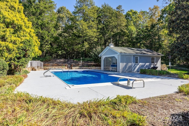 view of pool with a diving board and a patio area