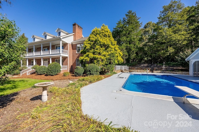 view of swimming pool with a diving board and a patio