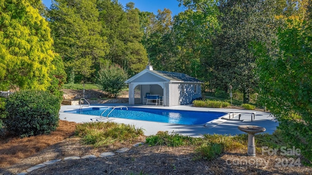 view of swimming pool with an outbuilding, a patio, and a diving board