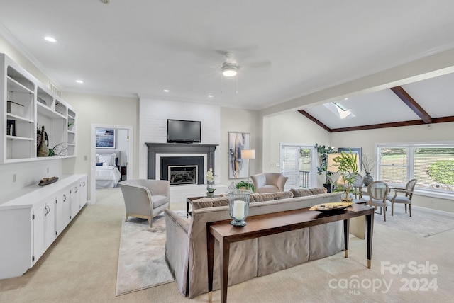 carpeted living room featuring a fireplace, ceiling fan, and vaulted ceiling with skylight