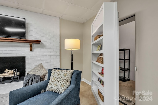 living area with a fireplace and a drop ceiling