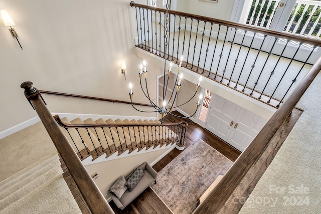 stairs featuring wood-type flooring and a chandelier