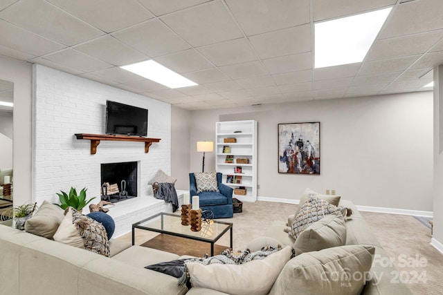 carpeted living room featuring a drop ceiling and a fireplace