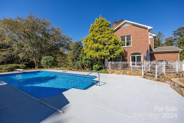 view of swimming pool featuring a diving board and a patio