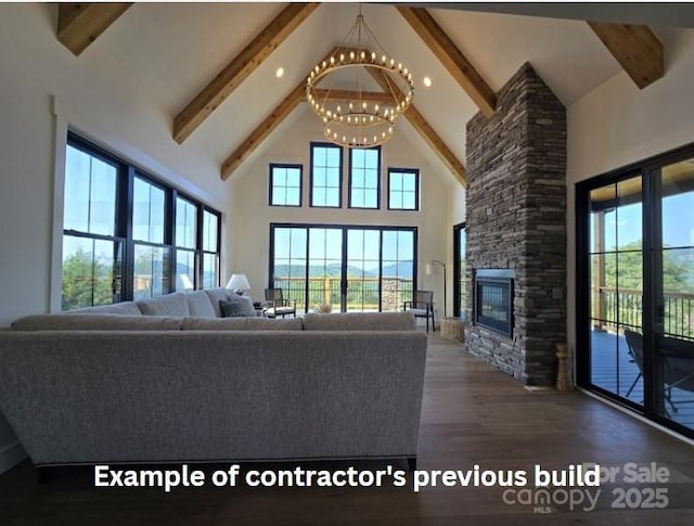 unfurnished living room featuring hardwood / wood-style floors, high vaulted ceiling, a stone fireplace, a healthy amount of sunlight, and a chandelier