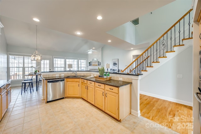 kitchen featuring dishwasher, dark stone countertops, vaulted ceiling, light brown cabinets, and recessed lighting