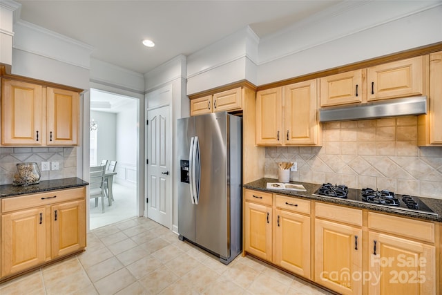 kitchen featuring black gas stovetop, dark stone countertops, stainless steel fridge, and under cabinet range hood