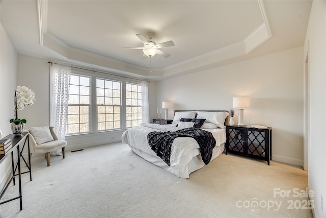 bedroom featuring ceiling fan, ornamental molding, a raised ceiling, and light colored carpet