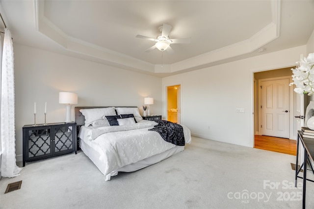 carpeted bedroom featuring ornamental molding, ceiling fan, a tray ceiling, and visible vents