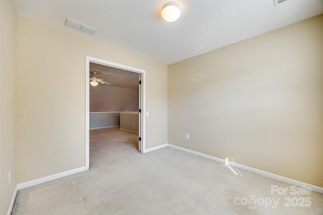 spare room with baseboards, visible vents, and light colored carpet