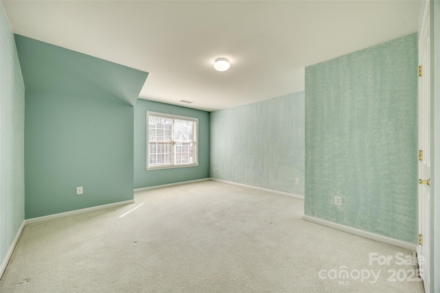 empty room featuring light carpet and baseboards