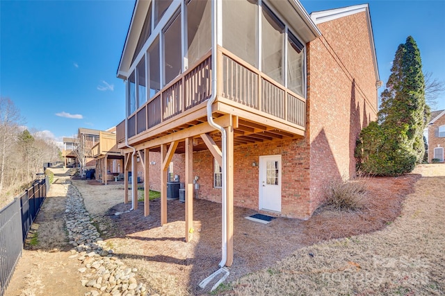 back of property featuring a sunroom, fence, cooling unit, and brick siding