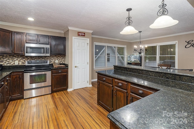 kitchen with ornamental molding, pendant lighting, appliances with stainless steel finishes, and light hardwood / wood-style flooring