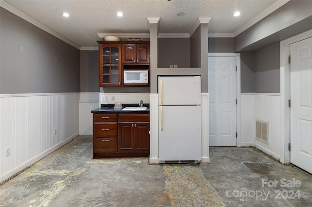 kitchen with sink, white appliances, a textured ceiling, and crown molding