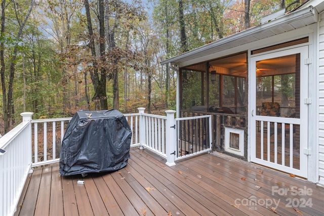 wooden deck with a sunroom and a grill