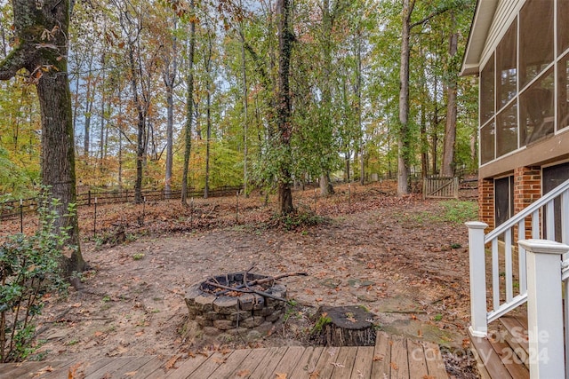 deck with a sunroom and an outdoor fire pit