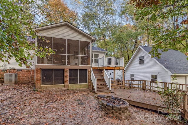 rear view of house with a deck, central air condition unit, a sunroom, and a fire pit