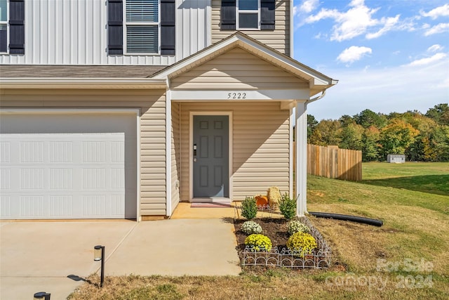 view of exterior entry featuring a lawn and a garage