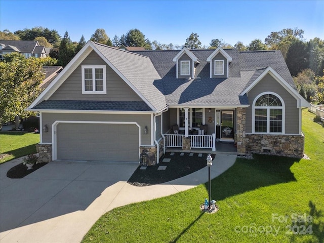 view of front of home featuring covered porch, a front yard, and a garage