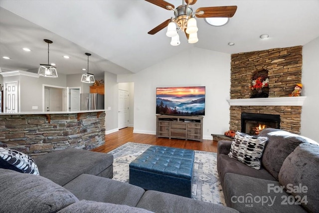 living room with dark hardwood / wood-style floors, ceiling fan, a stone fireplace, and vaulted ceiling