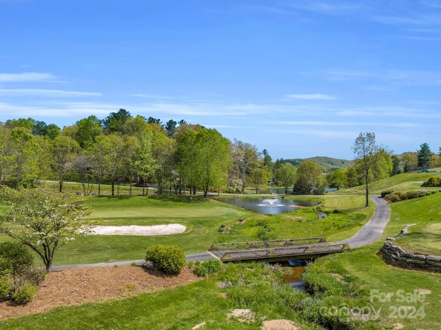 surrounding community with a water view and a lawn