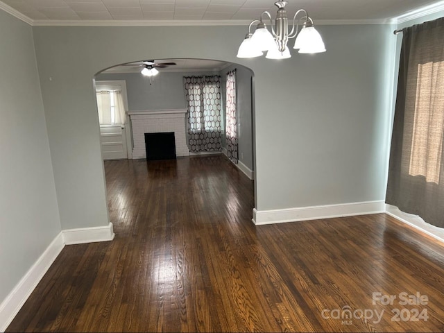 unfurnished dining area with ceiling fan with notable chandelier, crown molding, a fireplace, and dark hardwood / wood-style floors