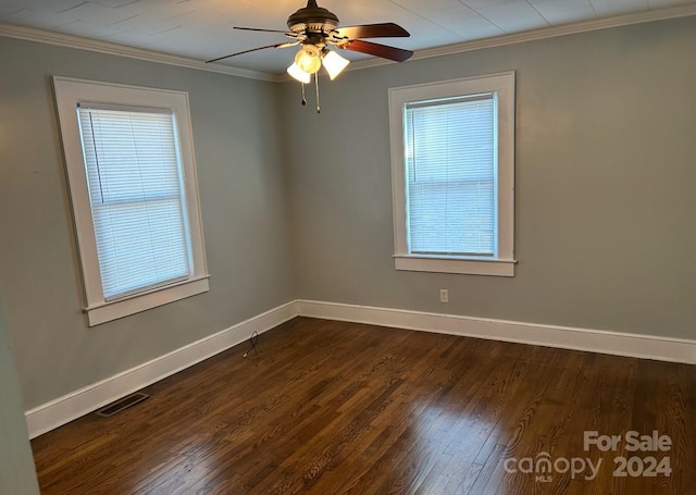 empty room featuring ornamental molding, ceiling fan, dark wood-type flooring, and a wealth of natural light