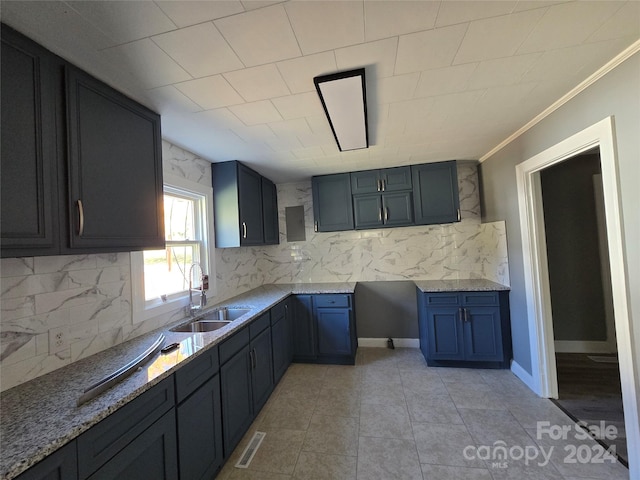 kitchen with light stone counters, light tile patterned flooring, sink, and backsplash