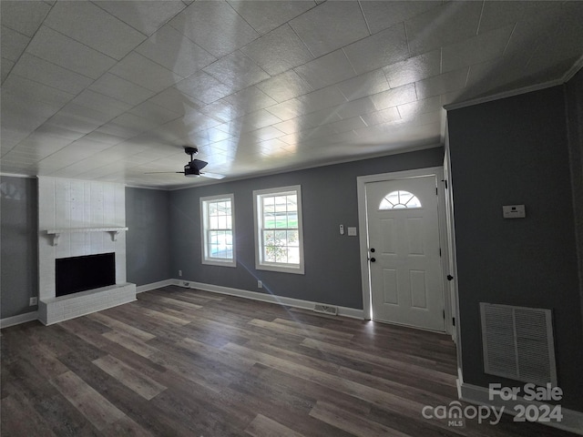 foyer entrance with crown molding, a brick fireplace, dark hardwood / wood-style floors, and ceiling fan